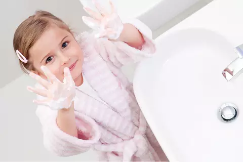 Kind am Waschbecken zeigt die Hände (Händehygiene)